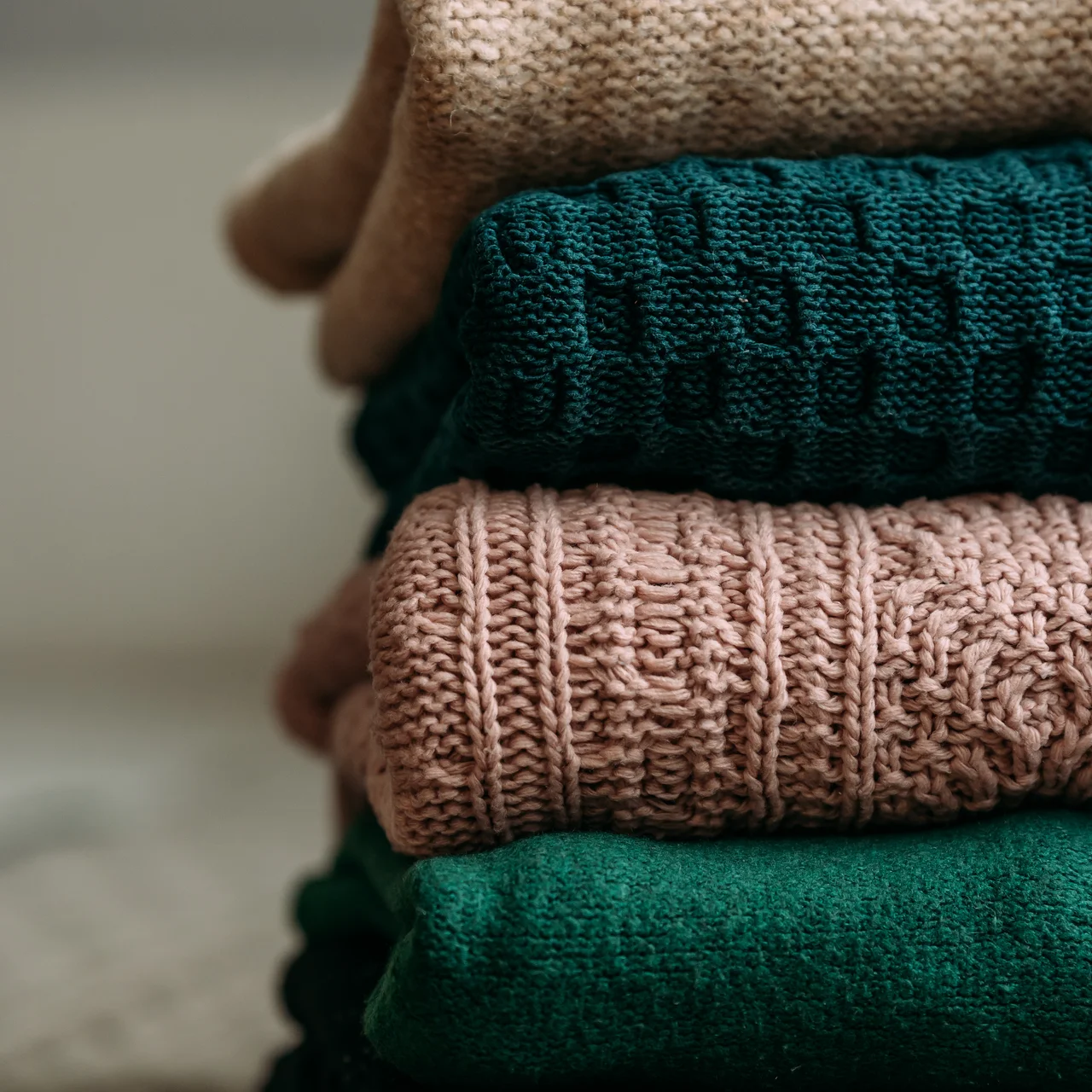Gestapelte Wollpullover in Beige, Grün und Rosa | © Andermatt Biogarten AG