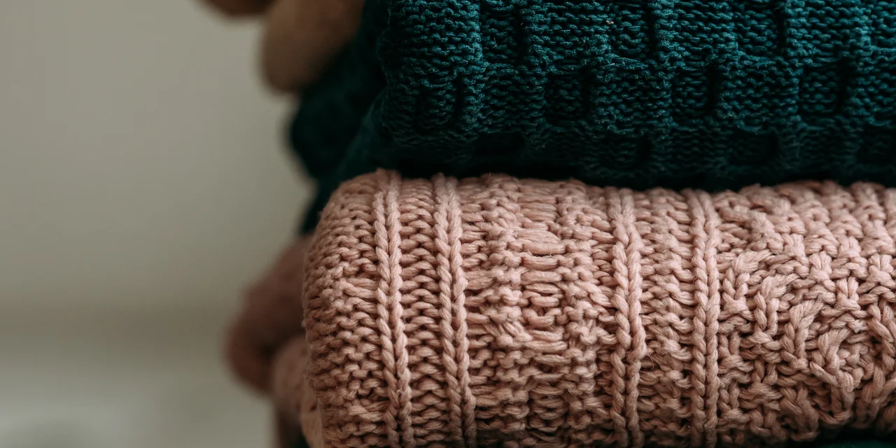 Gestapelte Wollpullover in Beige, Grün und Rosa | © Andermatt Biogarten AG
